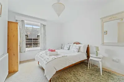 a white bedroom with a bed and a window at The Escape in Portinscale