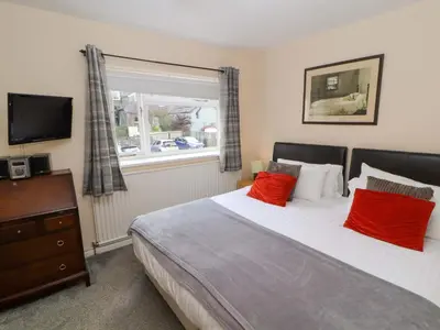 a bedroom with a bed with red pillows and a window at Brews Cottage in Keswick