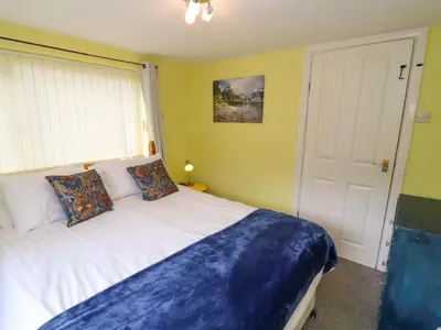 a bedroom with a white bed and a window at Brews Cottage in Keswick