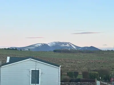 a white shed in a field with mountains in the background at Ralfgus 16 Forest Views caravan Park,Moota in Plumbland