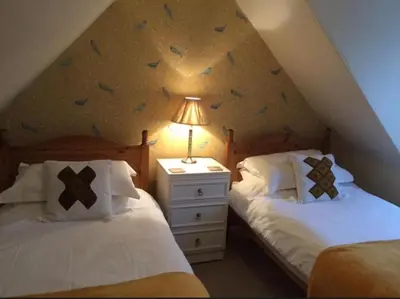 a attic bedroom with two beds and a lamp at Lazy Days in Moffat
