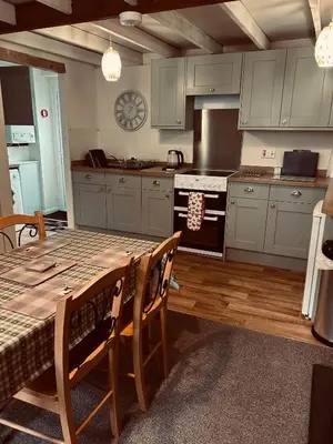 a kitchen with a table and a stove top oven at Lazy Days in Moffat