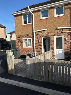 a brick house with a wooden fence in front of it at CosyHouse1 Private Parking Base for Lake District and Sellafield in Cleator