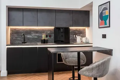 a kitchen with black cabinets and a table with two chairs at The Fairlie Suite No2 in Prestwick
