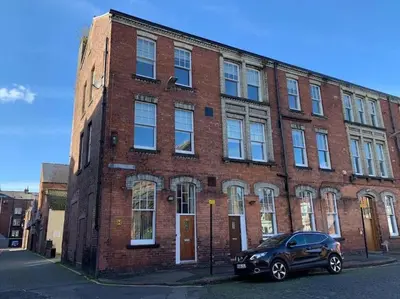 a brick building with a car parked in front of it at 10 Thurnams House in Carlisle