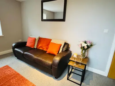 a brown leather couch in a living room with a mirror at New Road Apartment - 2 Bedrooms - Sleeps 3 in Whitehaven