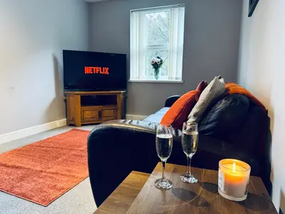 a living room with a leather couch and two wine glasses on a table at New Road Apartment - 2 Bedrooms - Sleeps 3 in Whitehaven