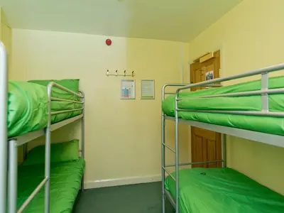 two bunk beds in a small room with green sheets at YHA Ennerdale in Buttermere