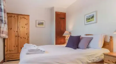a bedroom with a white bed with blue and purple pillows at Troutbeck Inn Cottages in Troutbeck