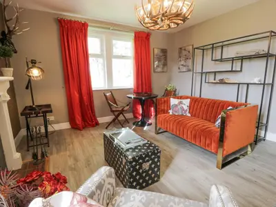 a living room with red curtains and a couch at Waterside Lodge in Lockerbie