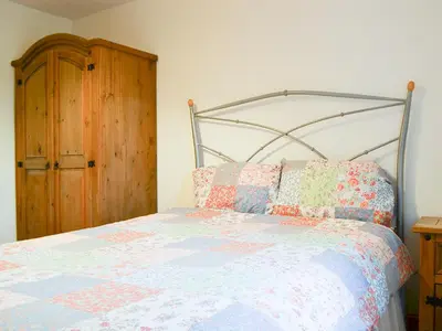 a bedroom with a bed and a wooden cabinet at Meadow Lodge-E4105 in Aspatria