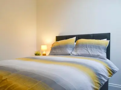 a bedroom with a large bed with yellow and white sheets at Sunset View-E4107A in Aspatria