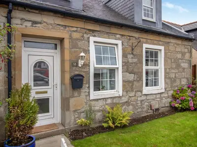 a stone house with a white door and windows at The Loans Inn Cottage in Loans