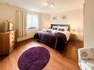 a bedroom with a large bed and a purple rug at Quare Place in Mainsriddle