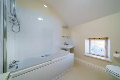 a white bathroom with a tub and a sink at 7 Low Glenridding - with private parking in Glenridding