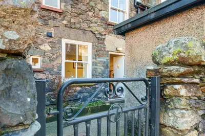 a black gate in front of a stone building at 7 Low Glenridding - with private parking in Glenridding