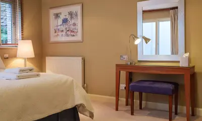 a bedroom with a bed and a desk and a mirror at Blencathra in Keswick