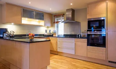 a kitchen with stainless steel appliances and wooden cabinets at Underscar - Stonethwaite in Keswick