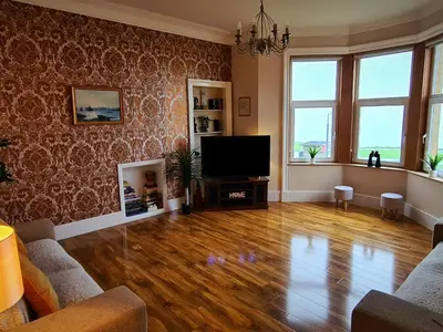 a living room with wooden floors and a flat screen tv at Ailsa View in Girvan