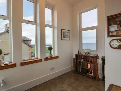 a room with windows and a book shelf with a clock at Ailsa View in Girvan