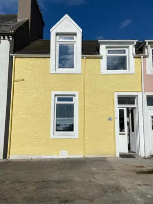 a yellow house with white windows on a street at 2 Bed seafront cottage in Portpatrick in Portpatrick