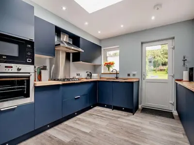 a large kitchen with blue cabinets and a window at 2 Bed seafront cottage in Portpatrick in Portpatrick