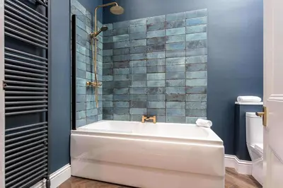 a bath tub in a bathroom with blue tiles at The Oliver in Ayr