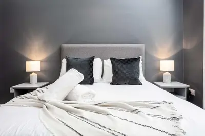 a bedroom with a white bed with two lamps at The Oliver in Ayr
