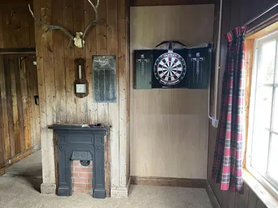 a corner of a room with a dart board and a wall at Garlies Lodge in Bargrennan