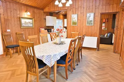 a kitchen and dining room with a table and chairs at Garlies Lodge in Bargrennan