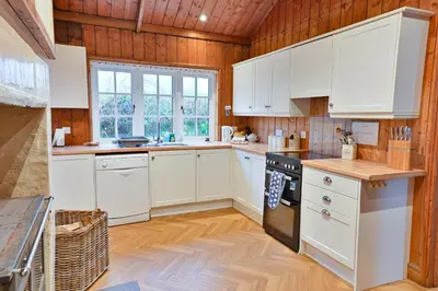a kitchen with white cabinets and wooden walls at Garlies Lodge in Bargrennan