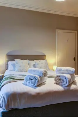 a bedroom with a bed with towels on it at The Fullarton - Coorie Doon Stays in Troon