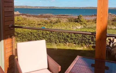a view of the ocean from the balcony of a house at Curlew Cottage in Gatehouse of Fleet