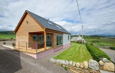 a small house with a porch and a yard at Curlew Cottage in Gatehouse of Fleet