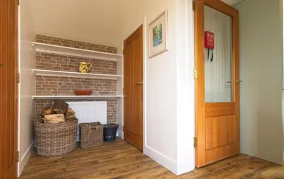 a living room with a brick fireplace and a door at Edenville Cottage in Gatehouse of Fleet