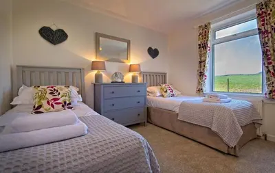 a bedroom with two beds and a window at Edenville Cottage in Gatehouse of Fleet