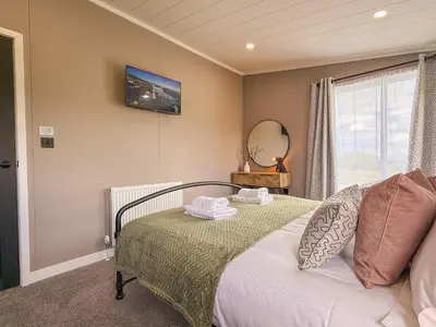 a bedroom with a bed with a mirror and a window at Dogwood Lodge in Bassenthwaite