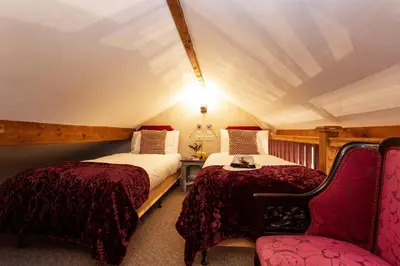 a bedroom with two beds and a chair at Scenery Hill Hideaways The Coach House Charming Retreat with Jacuzzi and BBQ Hut Near the Lake District in Workington