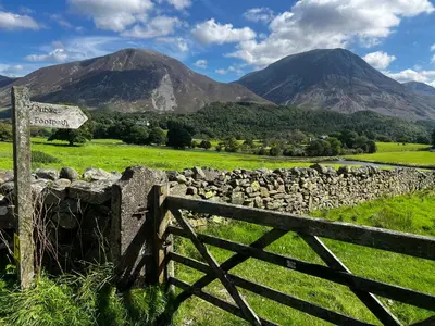 a fence and a sign with mountains in the background at Scenery Hill Hideaways The Coach House Charming Retreat with Jacuzzi and BBQ Hut Near the Lake District in Workington