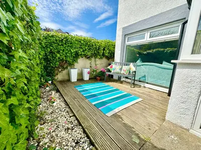 a mat on a patio with a couch and a window at Kennedy Cottage by Troon beach in Troon