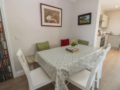 a dining room table with white chairs and a table cloth at Arthur's Cottage in Dumfries