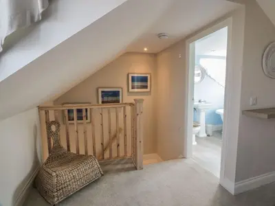 a room with a staircase with a chair and a bathroom at Arthur's Cottage in Dumfries