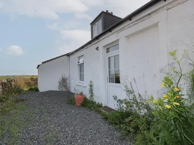 a white building with a window and a door at Powillimount Cottage in Dumfries