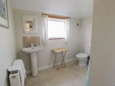 a bathroom with a sink and a toilet and a window at Powillimount Cottage in Dumfries