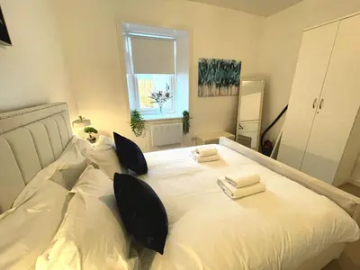 a large white bed with pillows and towels on it at Beautifully Presented Cosy Town Centre Cottage - Pass the Keys in Dumfries