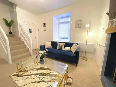 a living room with a blue couch and a glass table at Beautifully Presented Cosy Town Centre Cottage - Pass the Keys in Dumfries