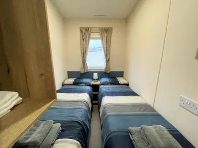 a room with three beds in it with a window at Cosy 3BR Getaway in Beautiful Country Park - Pass the Keys in Beattock