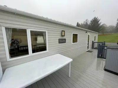 a white bench sitting on the deck of a house at Cosy 3BR Getaway in Beautiful Country Park - Pass the Keys in Beattock