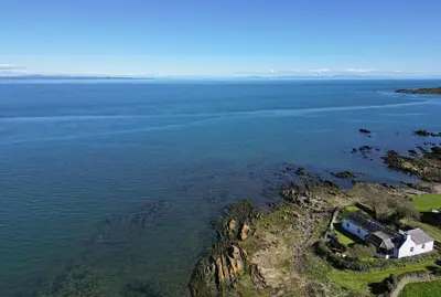 an aerial view of a house on a cliff in the water at Shell Cottage in Whithorn