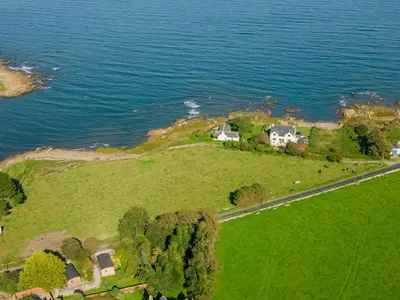 an aerial view of a house on an island in the water at Shell Cottage in Whithorn